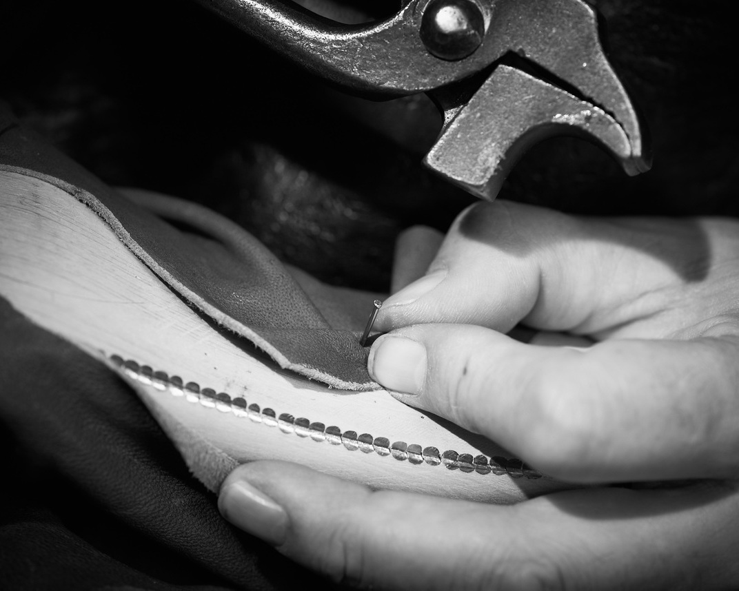 Montage d'une chaussure en cuir à la pince, gros plan sur les mains et les coutures.